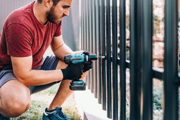 A professional working on fence building is using power tool.