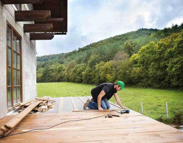 Professional deck builder installing wood decking for a custom outdoor living space