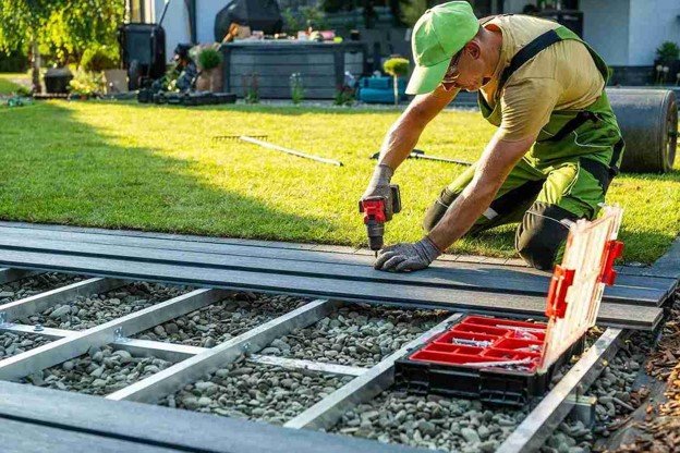 Deck installer securing composite decking boards over a metal frame during deck installation in Wylie, TX