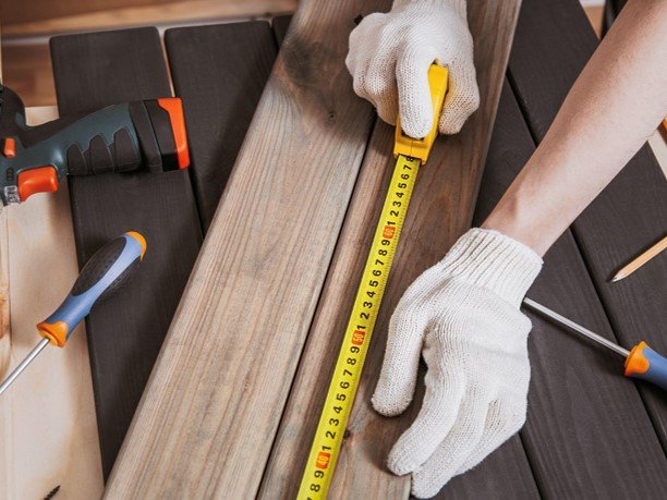 A measuring tape with a professional working for wood deck