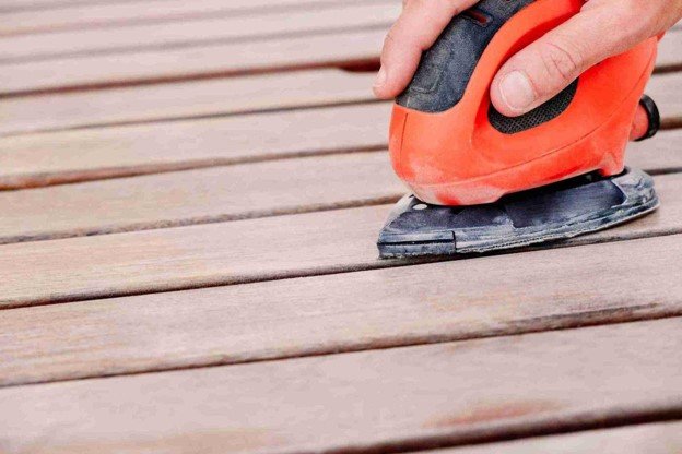 Power sander removing the worn surface from wood deck boards during deck cleaning and restoration in Wylie, TX