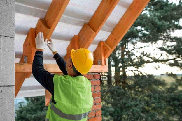 Contractor installing overhead wood beams during a residential pergola construction project.